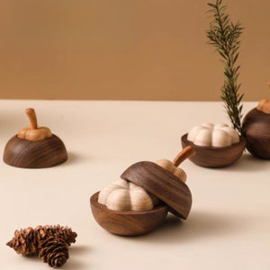 A wooden mangosteen diffuser lifestyle shot with a pine cone on a beige background