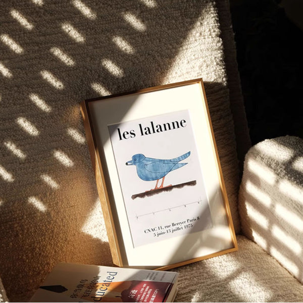 Brushed gold aluminum frame with a bluebird illustration on a textured surface with sunlight casting shadows.