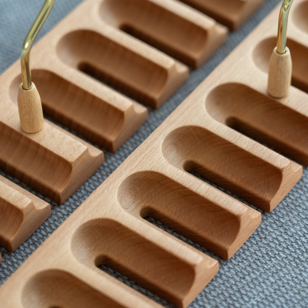 Close-up of a wooden belt rack with gold hangers on a blue fabric background