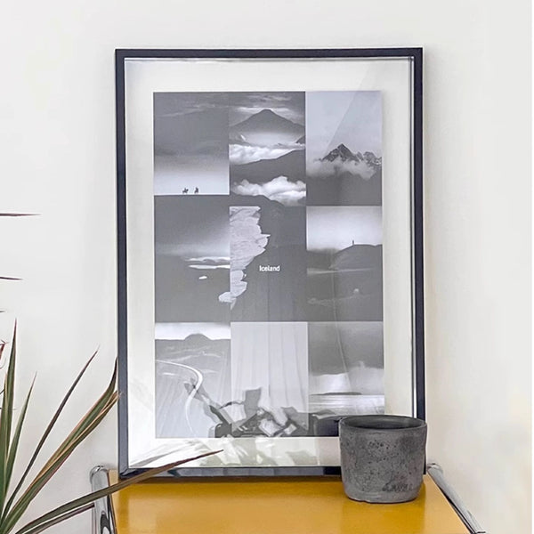 Acrylic framed black and white landscape print on a wall with a plant and pot below.