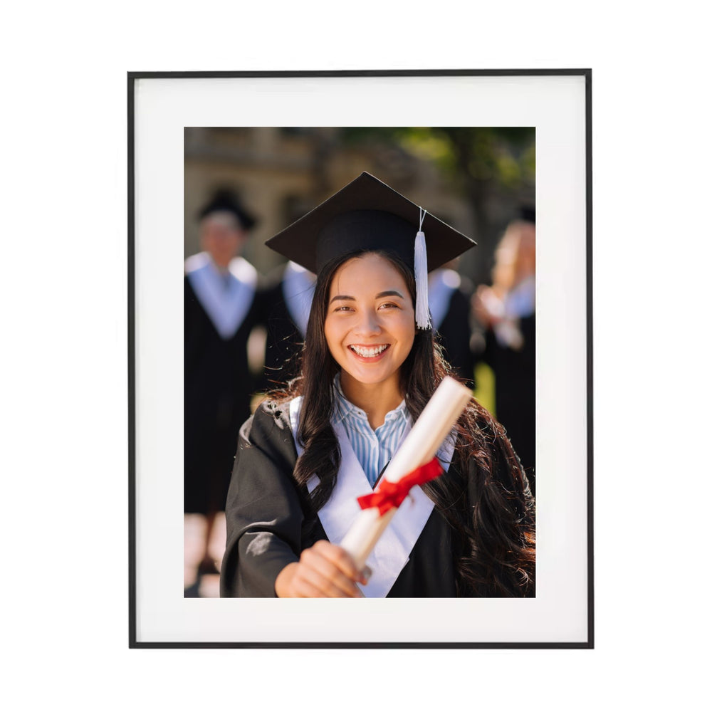 Black aluminum-framed photo of a graduate holding a diploma with a blurred background