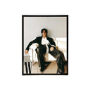 Black acrylic picture frame showing a person sitting on a couch wearing a black suit with a white shirt, framed with a black border.