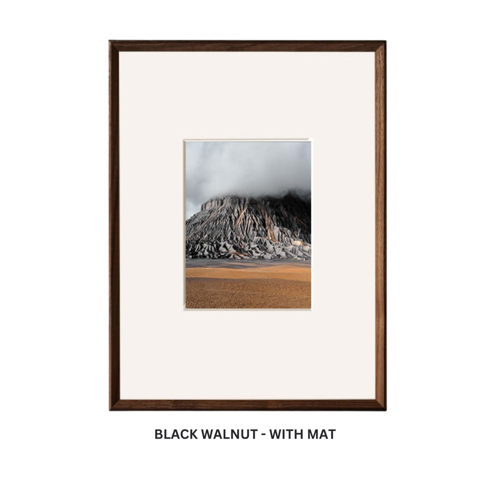 Framed photograph of a mountain landscape on a white background. Black walnut beveled picture frame with mat.