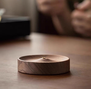 Black walnut incense holder on a dark surface with a blurred background