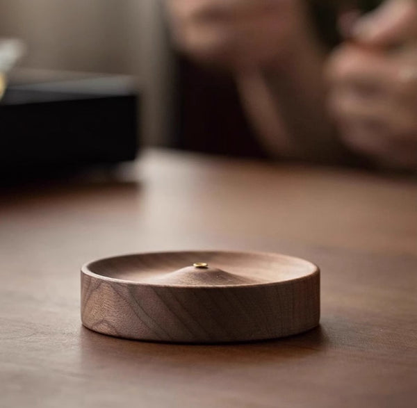 Black walnut incense holder on a dark surface with a blurred background