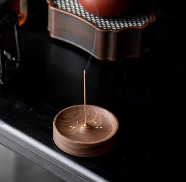 Wooden incense holder with a single stick on a dark surface