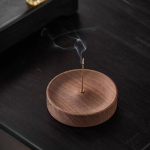 Black walnut incense holder with a smoking incense stick on a dark surface