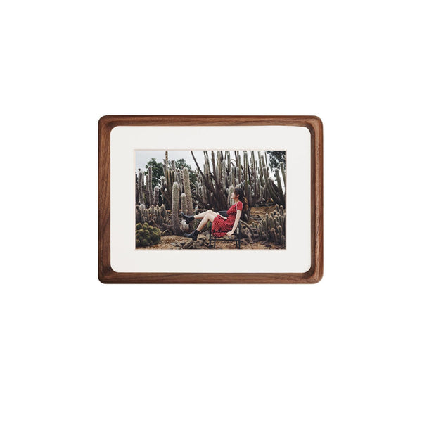 Framed black walnut picture of a person  in a cactus field on a white background