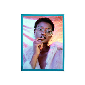 Teal, blue, thick acrylic picture frame with the picture of a person wearing glasses and a fur coat with a colorful background