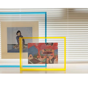 Thick blue and yellow acrylic picture frame with a window blind background