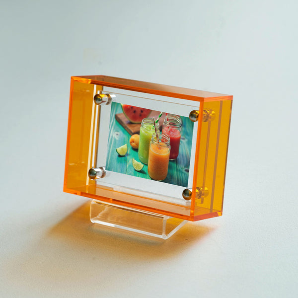 Transparent orange photo frame with a glass insert on a light gray background