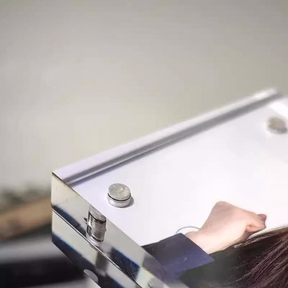 Close-up of a magnetic acrylic picture frame with a hand interacting with it, on a neutral background.