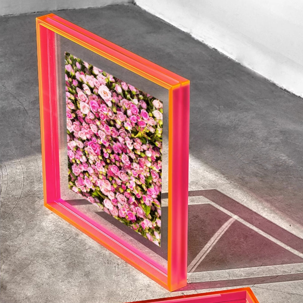 Floral wall art with an electric pink frame on a concrete floor.