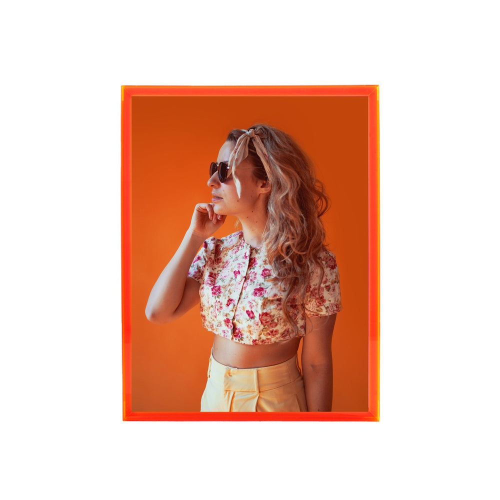Electric pink thick acrylic picture frame showing a woman wearing a floral shirt and sunglasses against an orange background