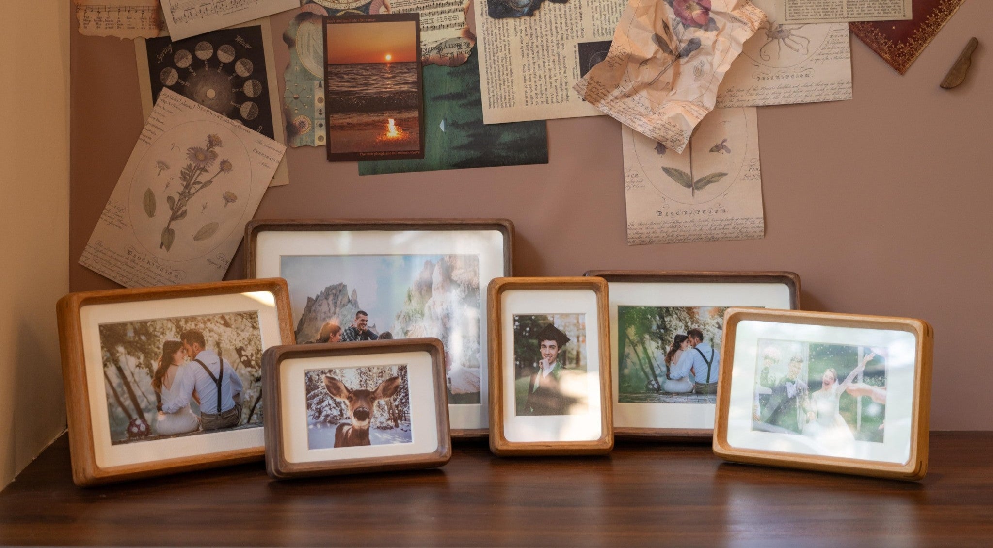 Collection of framed photos and vintage papers on a wooden surface with a brown wall background.