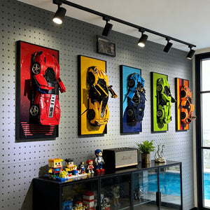 Wall with ONE MAAY framed colorful LEGO Supercar models and a display cabinet below.