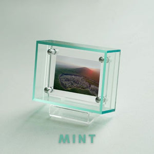 Clear light green picture frame with a scenic image on a light gray background, featuring the brand 'Mint'.