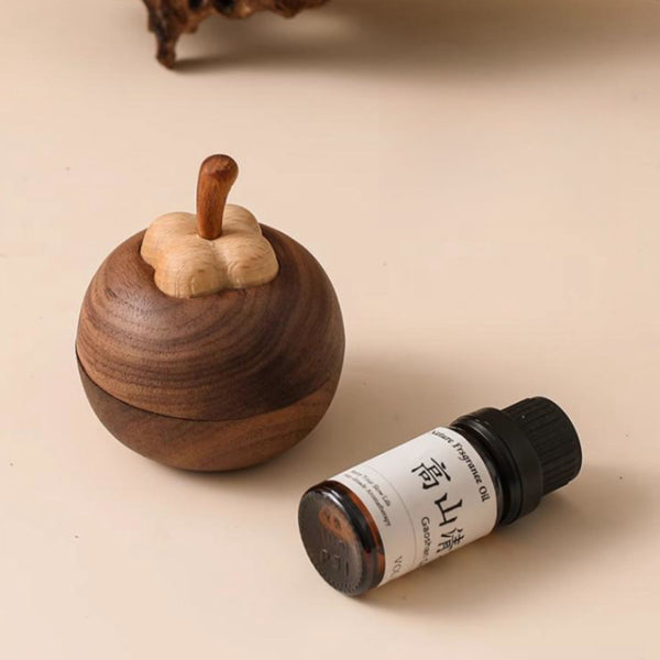 A wooden mangosteen diffuser next to a small bottle on a beige background