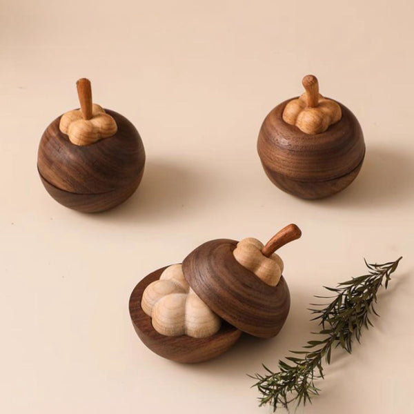 Three wooden mangosteen diffusers on a beige background with a sprig of rosemary.
