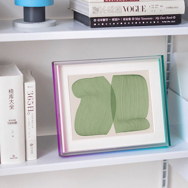 Framed artwork with green abstract design on a shelf with books. Ombre acrylic picture frame table top display. 