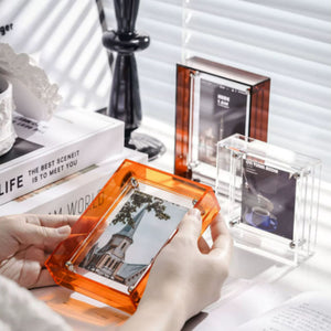Person holding an orange transparent photo frame with a church image on a desk. 