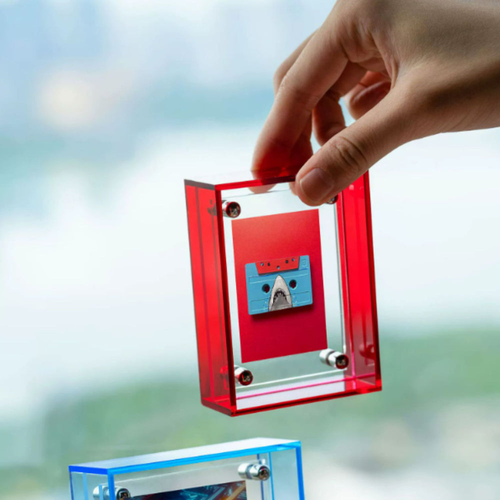 Red acrylic transparent picture frame with a blue cassette tape inside on a white background
