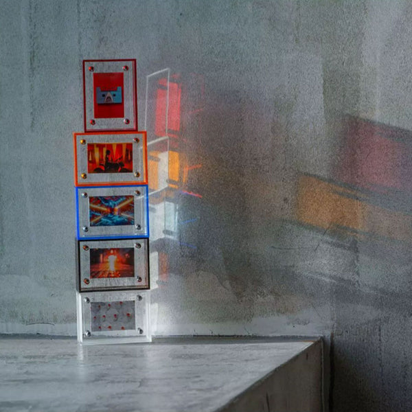 Stack of colorful acrylic picture frames on a textured wall. Red, orange, blue, brown and white.