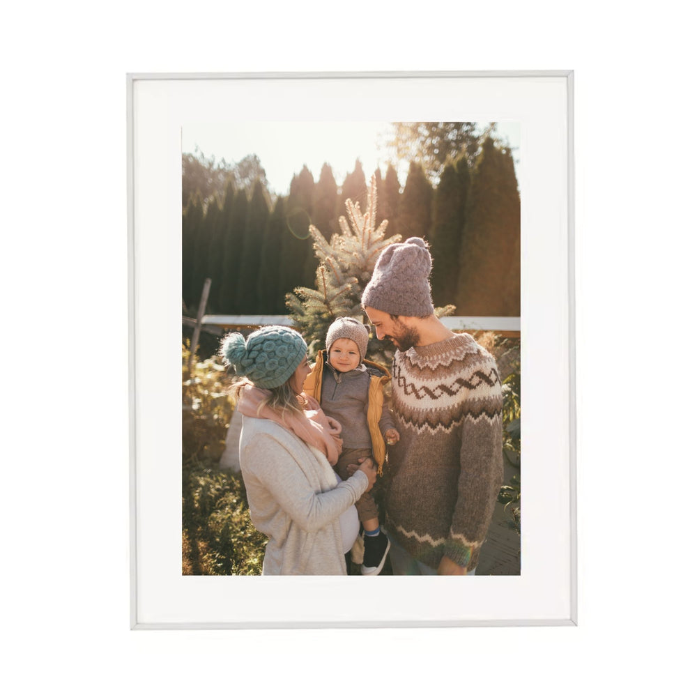 Metal-framed photograph of a family outdoors with trees in the background
