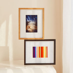 Two framed artworks on a beige wall. Teak and Black Walnut table top picture frames.