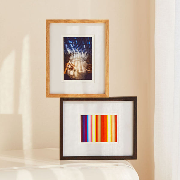 Two framed artworks on a beige wall. Teak and Black Walnut table top picture frames.