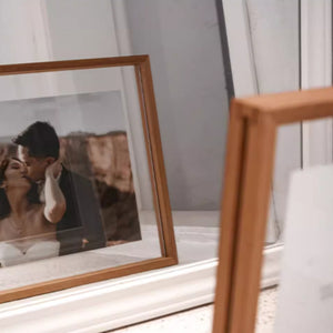 Teak-framed photograph of a couple kissing in a wooden frame on a shelf.
