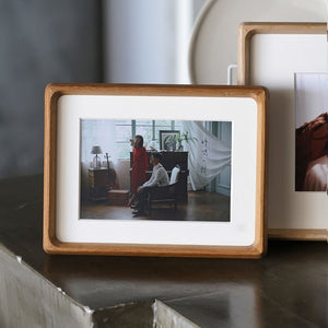 A teak picture wooden picture frame with a photograph of two people in a room.