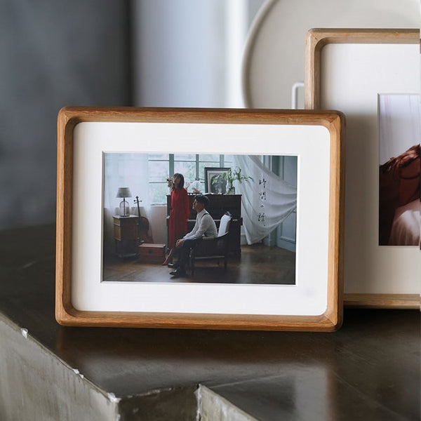 A teak picture wooden picture frame with a photograph of two people in a room.