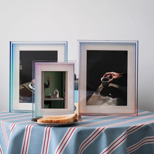 Three acrylic ombre framed pictures on a table with a striped tablecloth