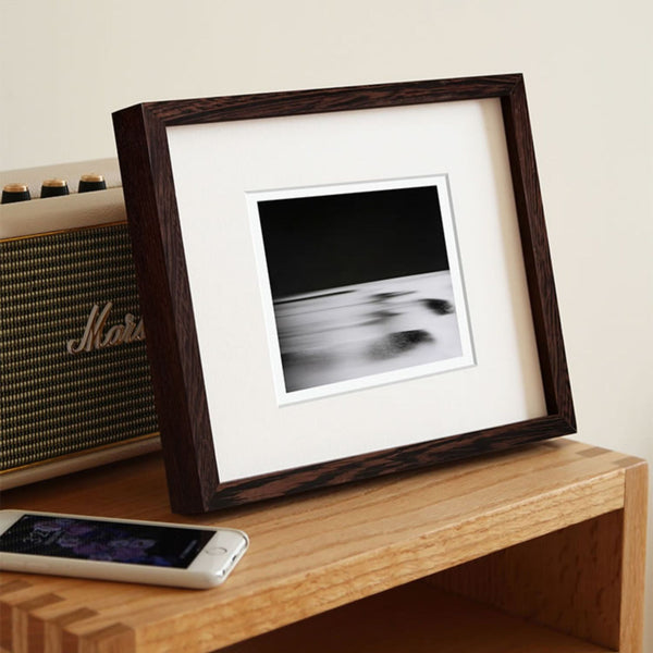Framed black and white photo on a wooden surface next to a Marshall amplifier and smartphone. Black wenge picture frame.