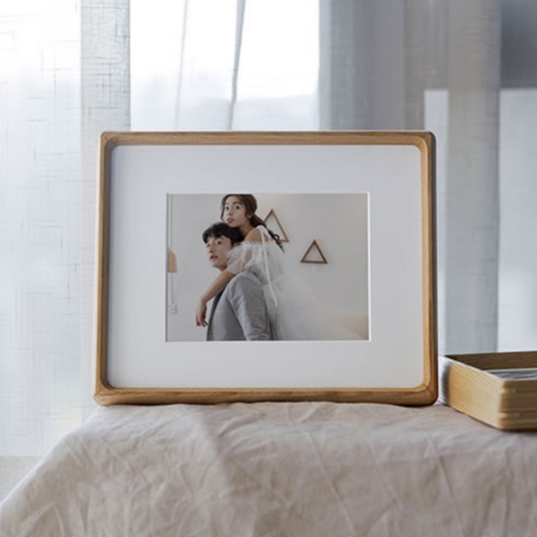 White ash wooden photo frame with a picture of two people on a bed