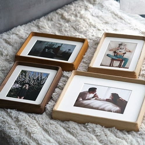 Four wooden picture frames with photos on a soft surface, white ash, teak, black walnut