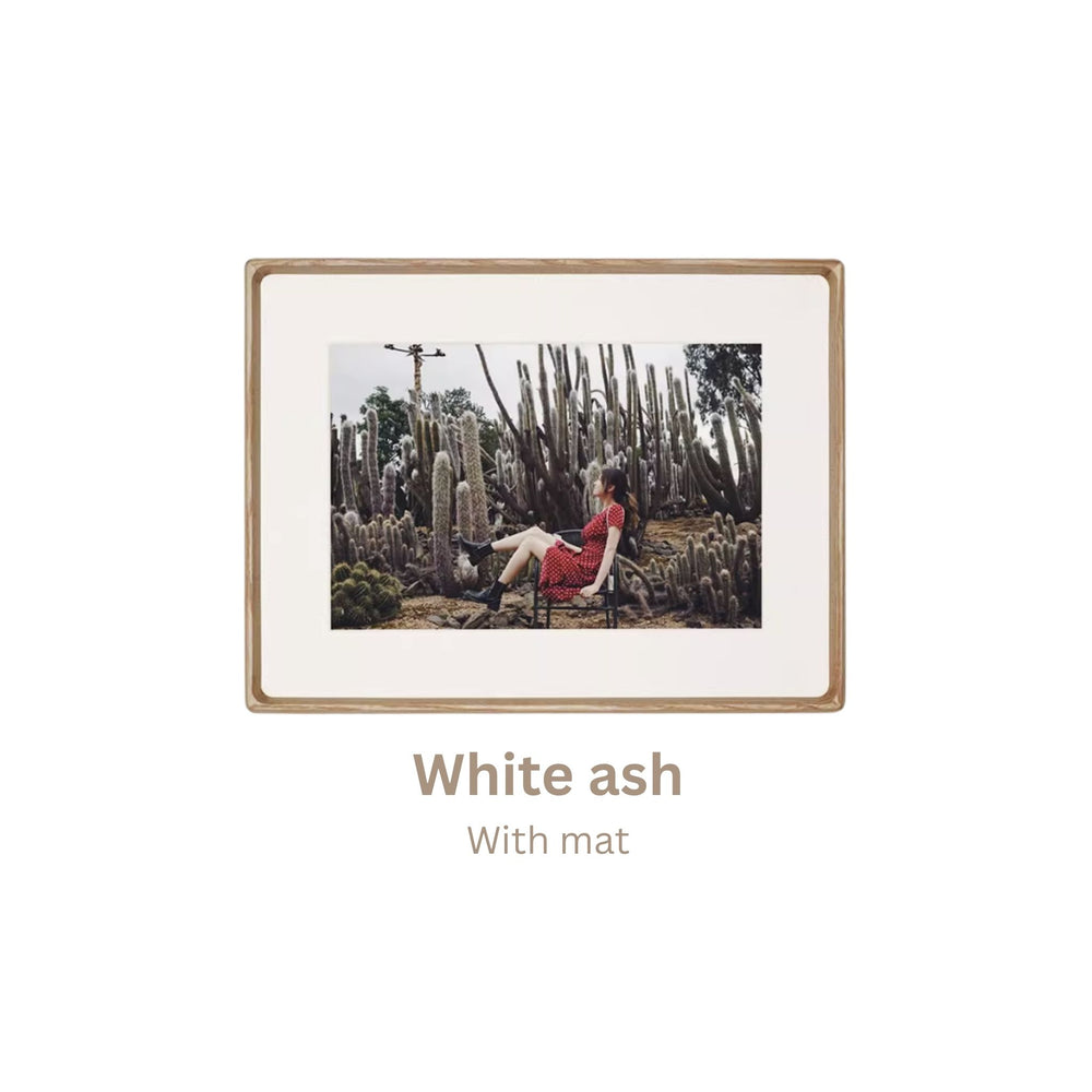 White ash wood-framed photograph of a person in a red dress sitting among cacti with 'White ash' frame text.