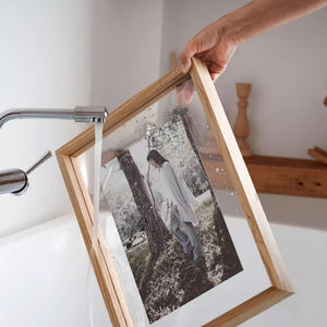 Person holding a wooden-framed photograph of a person in a park. White ash wood. 