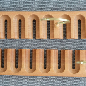 Wooden belt hanger close up shot with multiple slots on a textured gray background