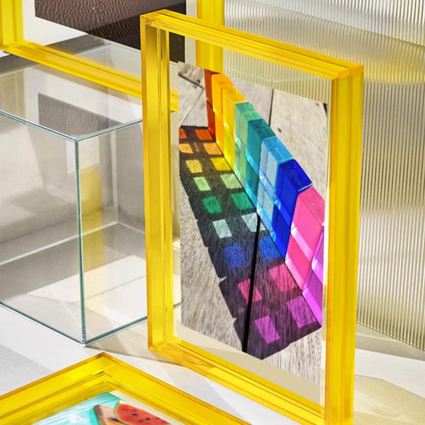 Colorful geometric art piece in a yellow frame on a glass surface.