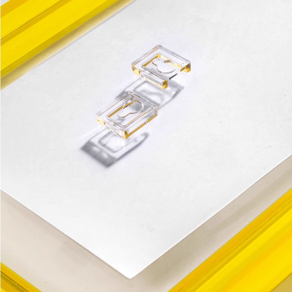 Colorful geometric art piece in a yellow frame on a glass surface.