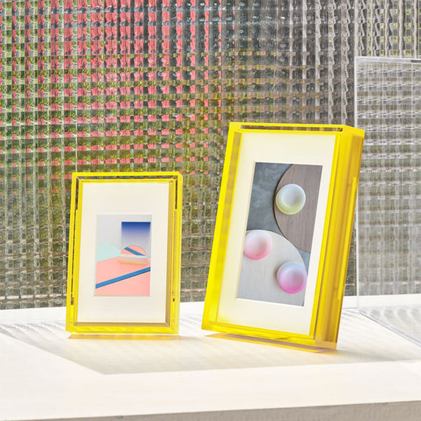 Two yellow-framed artworks on a surface with a textured wall background