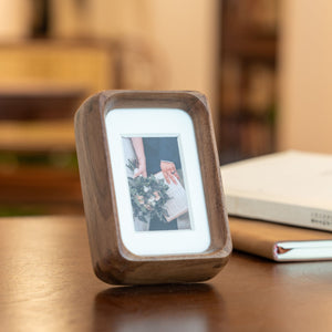 Wooden mini black walnut photo frame displaying a picture on a wooden surface. 2.2in x 3.3in. Polaroid fitting.