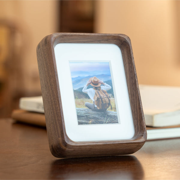 Wooden mini black walnut photo frame displaying a picture on a wooden surface. 3in x 4in. Polaroid fitting.