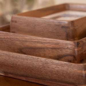 Wooden photo frames stacked together with a plant in the background