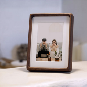 black walnut wooden photo frame with a couple on a couch inside, on a light surface.