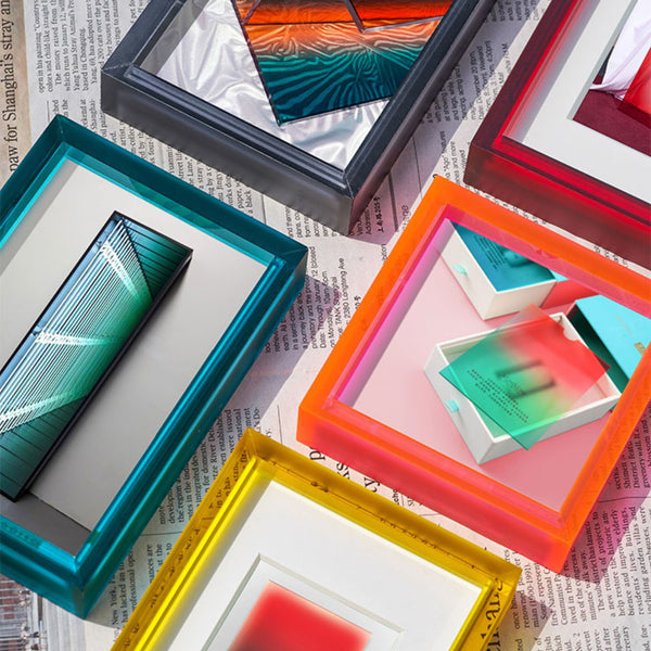 Colorful picture frames with artworks on a newspaper background, blue, graphite, red, electric pink, lemon yellow