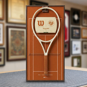 A ONE MAAY French Open-inspired red clay court tennis racket wall display mounted elegantly next to a wooden bookshelf in a home library, featuring a brown side banner that reads "French Open"