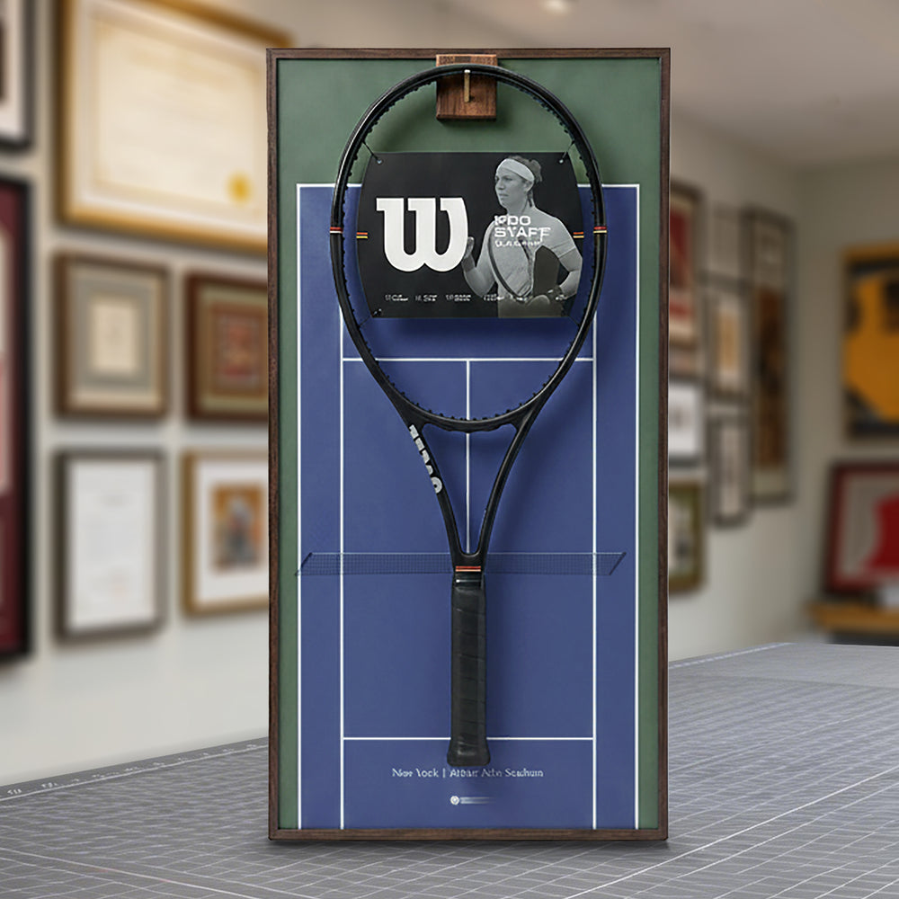 A ONE MAAY US Open-inspired blue hard court tennis racket wall display mounted elegantly next to a wooden bookshelf in a home library, featuring an olive-green side banner that reads "US Open"